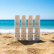 Four white Full Noon Mineral Sunscreen SPF 50 bottles lined up against a tan cardboard background.